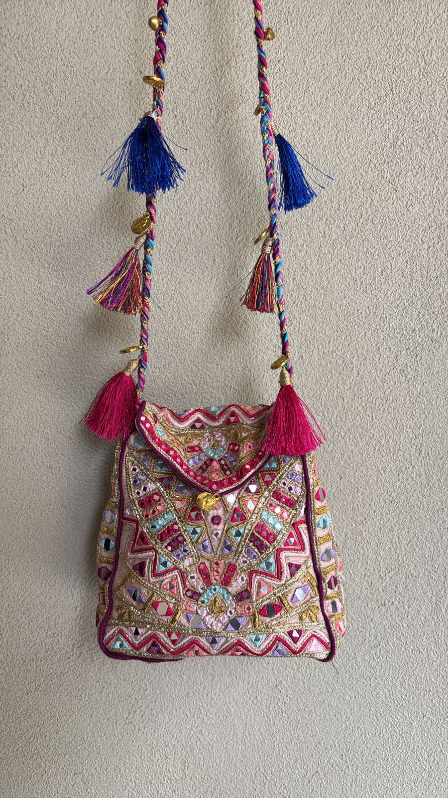 "Peach multi colored bag with resham, gotta, dori, mirror work and tassel detailing on the sling "