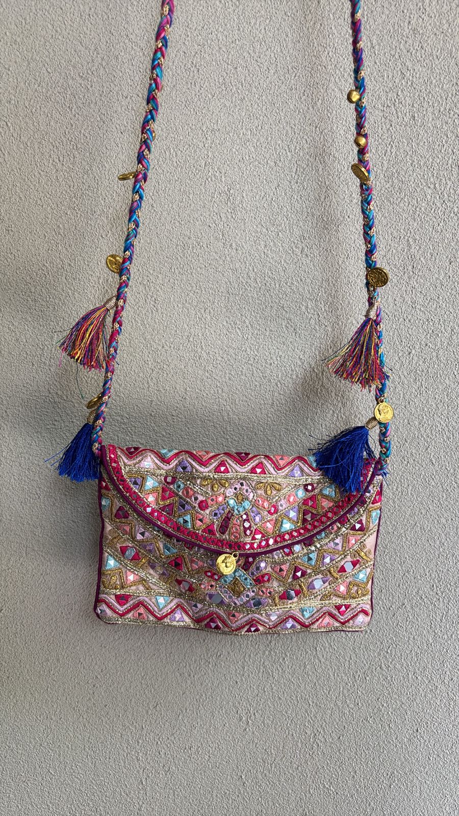 Light pink multicolored envelope sling bag with resham, mirror embellishments, braided dori strap, and vibrant tassel accents